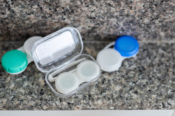 Accessories for working with contact lenses. Tweezers with contact lens and plastic container on gray background