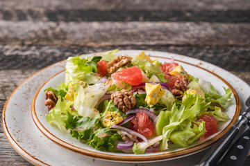 Fruit salad with garpefruit, cheese, lettuce and walnut on a plate. Diet and healthy salad