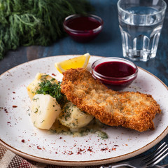 Crust chicken fillet with potato on aplate.