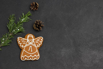 Christmas gingerbread cookie in shape of angel, green topping on black background, holiday cookies.