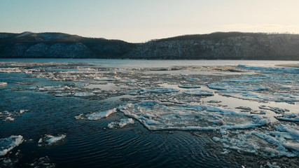 aerial view. Footage of the freezing river, in the given bare mountains covered with snow. A cold winter landscape. season