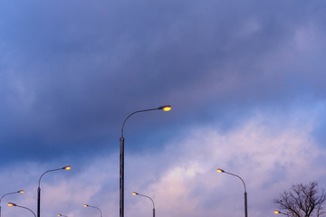 Abstract landscape. A row of street lights against a dusky cloudy sky.