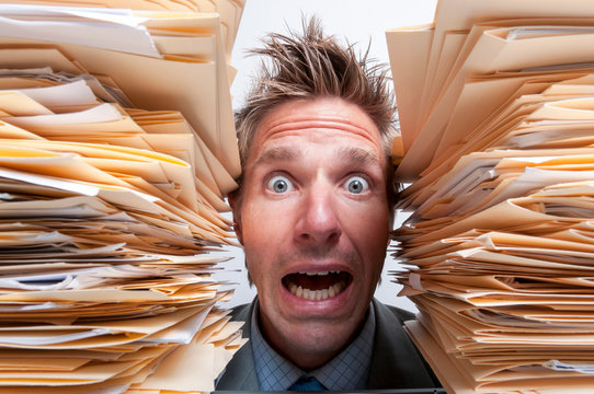 Stressed office worker screaming for help from between two massive stacks of file folders