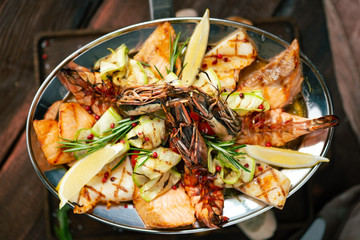 Grilled Mixed Seafoods set in metal plate with shrimp, salmon, squid and perch.