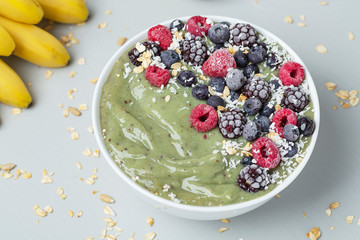 Healthy summer breakfast. Detox Green Smoothie with granola, kiwi, banana, spirulina and frozen berries. Vegetarian diet