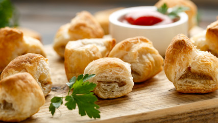 Pork sausage rolls with mustard and ketchup sauce on wooden board