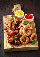 Sticky glazed chicken wings and deep fried battered onion rings served with lemon wedges, tomato ketchup and mustard. Greasy, fast food concept