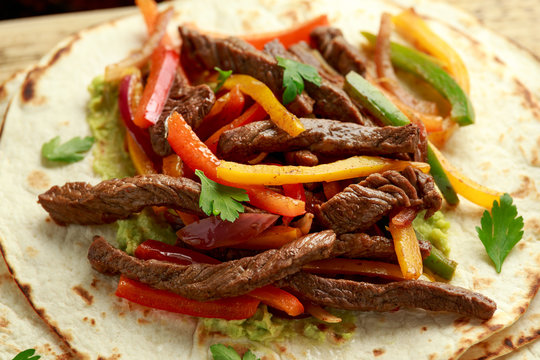 Beef Steak Fajitas with tortilla mix pepper, onion and avocado on wooden board
