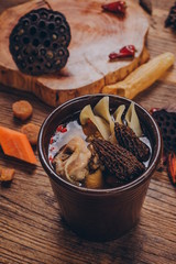 In a traditional Asian style, a black stone bowl holds a health stock made from goji berries, ginger, tripe and lobster.