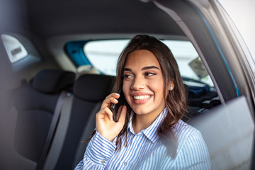Fototapeta na wymiar Cute young woman traveling. Attractive business woman in car. Talking on her mobile phone. Happy business woman talking on phone. Cheerful pretty young woman talking on phone and look straight ahead.