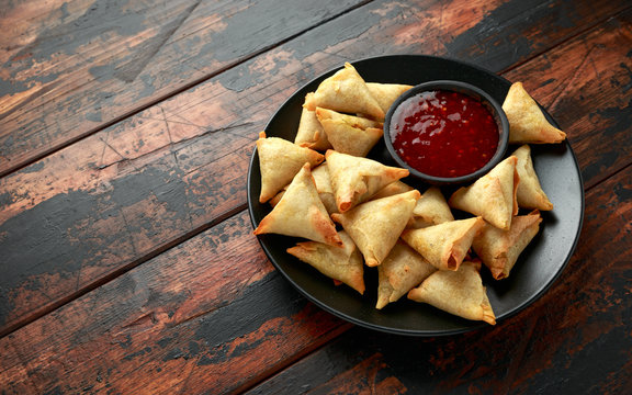 Fresh Indian Samosa with dipping sweet chili sauce on wooden table
