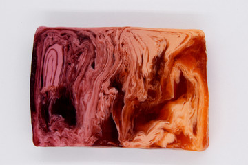 Abstract, multi-colored bar of handmade soap placed on a white background.