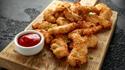 Buttermilk chicken nuggets with ketchup on wooden board