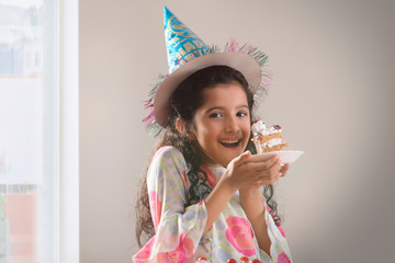 Portrait of a young girl eating her birthday cake. (Children)  	