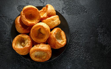 Traditional English Yorkshire pudding side dish on black plate and background - Powered by Adobe