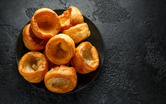 Traditional English Yorkshire pudding side dish on black plate and background