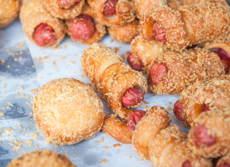 Bread with sausage rolls.Variety of sausage baked in dough on the table.roll with sausage close up on a paper