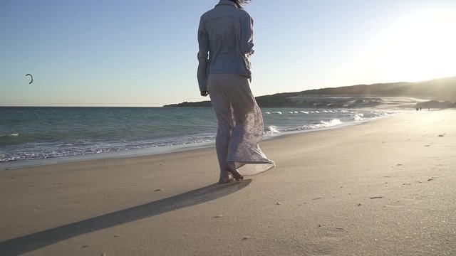 Mujer sola con vestido paseando por la playa en el atardecer HD