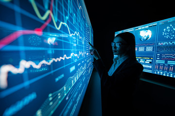 The business lady standing near the sensor screen in the dark laboratory