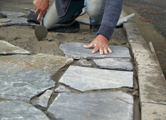 worker on construction site buildingsidewalk with traditional natural stones