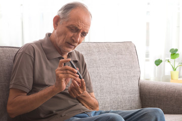 Senior man taking his diabetes test at home. (Health and fitness) 