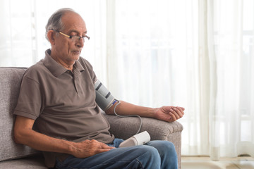 Senior man taking his blood pressure test at home. (Health and fitness)  - obrazy, fototapety, plakaty