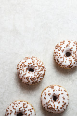 Donuts with suger icing and chocolate chips on a grey background with negative space.