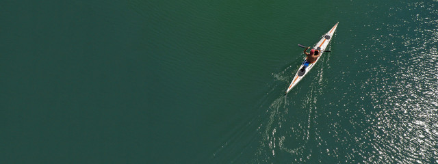 Aerial drone ultra wide photo of fit athletes practising sport kayak in tropical exotic lake with emerald water
