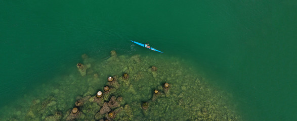 Aerial drone ultra wide photo of fit athletes practising sport kayak in tropical exotic lake with emerald water