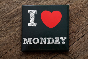 I Love Monday written on black note with wood background