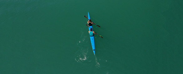 Aerial drone ultra wide photo of fit athletes practising sport kayak in tropical exotic lake with emerald water