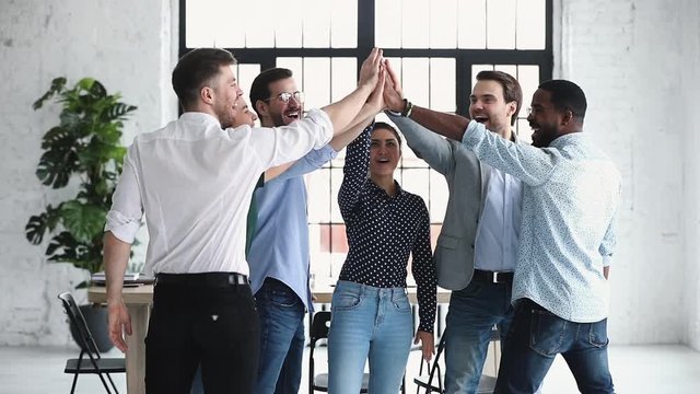 Happy diverse business team give high five together, slow motion