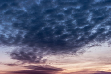 Dark cumulus clouds float through the sky before sunrise.