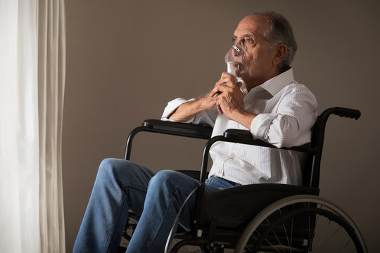 Senior Man Sitting On A  Wheelchair With An Oxygen Mask. (Health And Fitness) 