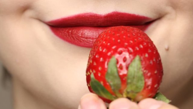 Woman imitates masturbation. Sensual red lips is licking strawberry. Sexy woman's tongue and lips
