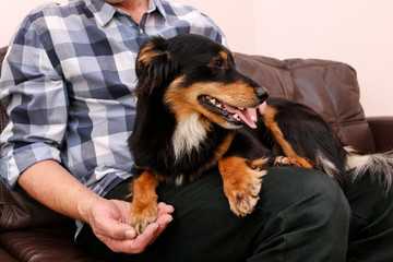 A man is sitting on the sofa with his beautiful young, black dog.