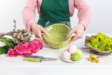 Woman shows how to make Easter table decoration with roses, moss and catkins