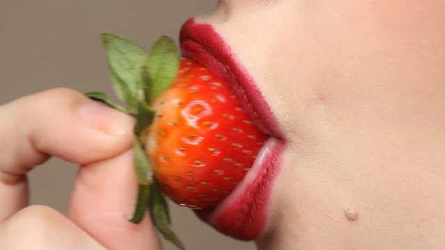Woman imitates masturbation. Sensual red lips is licking strawberry. Sexy woman's tongue and lips