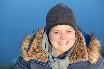 Closeup portrait of smiling lady. She is outdoors wearing winter clothes.