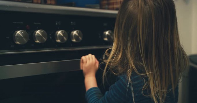 Toddler helping his mother turn on the oven