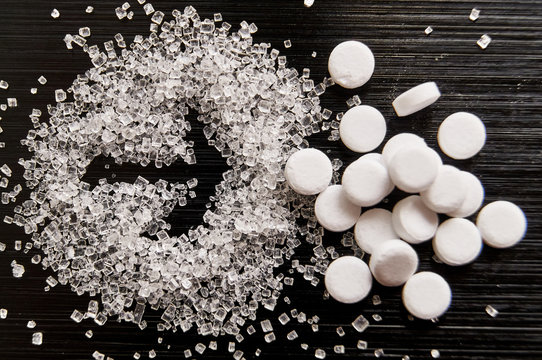 sweetener tablets lying with sugar on a dark background