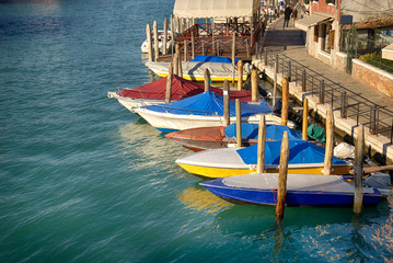 Fototapeta na wymiar Motor boats anchored in colorful shopping street in Venice, Italy.