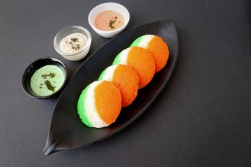 Tiranga Idli or Tricolor Idly cooked in  Indian National Flag colors - saffron or orange, white and green. Served with tiranga chutney. Concept for Indian Independence or Republic day greeting card. 