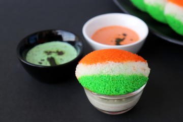 Tiranga Idli or Tricolor Idly cooked in  Indian National Flag colors - saffron or orange, white and green. Served with tiranga chutney. Concept for Indian Independence or Republic day greeting card. 