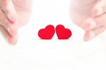 Two red heart with protection by hands on white background