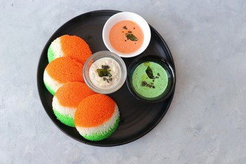 Tiranga Idli or Tricolor Idly cooked in  Indian National Flag colors - saffron or orange, white and green. Served with tiranga chutney. Concept for Indian Independence or Republic day greeting card. 