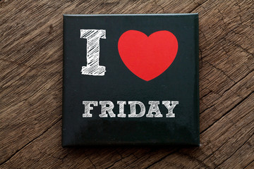 I Love Friday written on black note with wood background