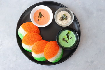 Tiranga Idli or Tricolor Idly cooked in  Indian National Flag colors - saffron or orange, white and green. Served with tiranga chutney. Concept for Indian Independence or Republic day greeting card. 