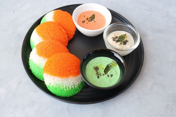Tiranga Idli or Tricolor Idly cooked in  Indian National Flag colors - saffron or orange, white and green. Served with tiranga chutney. Concept for Indian Independence or Republic day greeting card. 