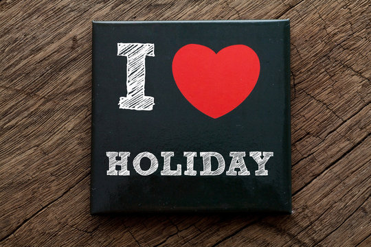 I Love Holiday written on black note with wood background